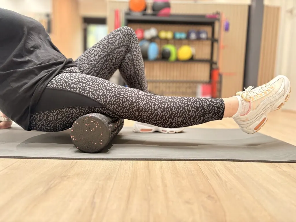 Oefening met een foamroller onder de benen op de mat